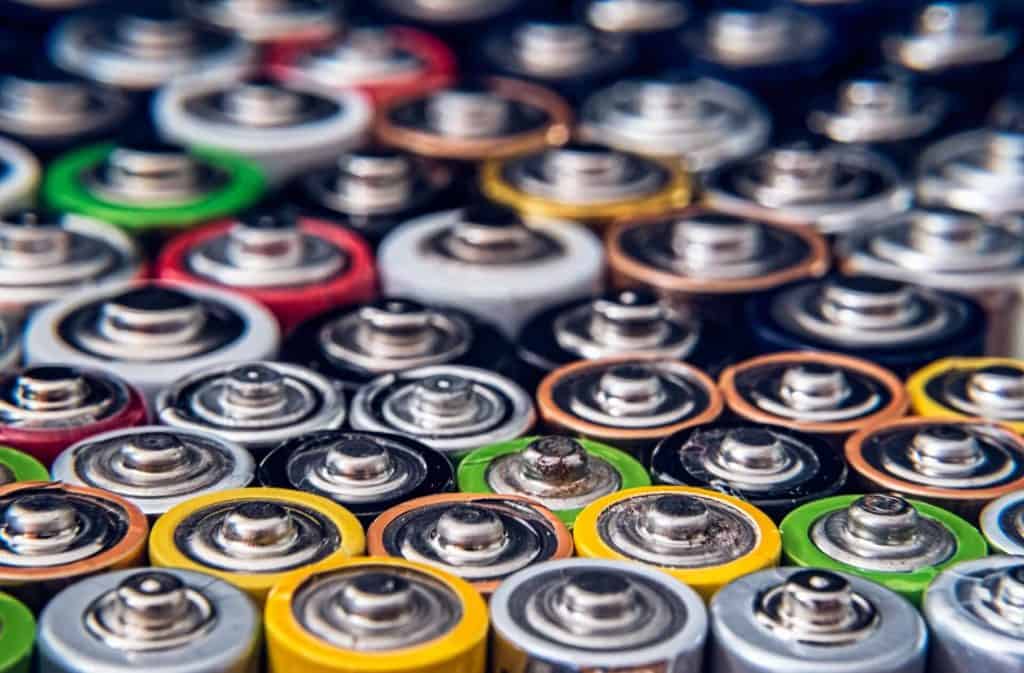 A close-up view of various used batteries in different sizes and colors, arranged closely together. The tops of the batteries are visible, showcasing metal terminals and a variety of colored casings, highlighting the importance of proper electronic recycling in Atlanta GA.