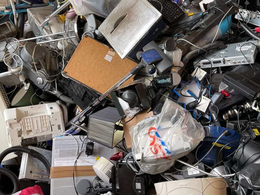 A cluttered pile of assorted electronic waste, including keyboards, computers, cables, and miscellaneous gadgets, is stacked haphazardly. This e-waste jumble highlights the need for electronic recycling in Atlanta GA to manage the tangled mass of various shapes and sizes.
