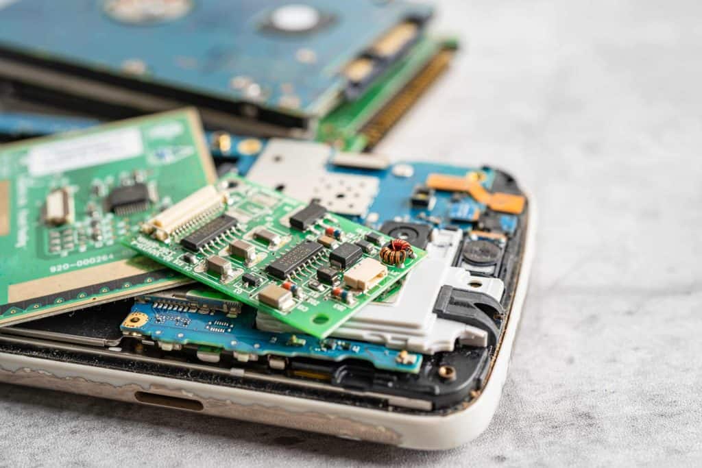 Close-up of various dismantled electronic components, including green circuit boards and hard drive parts, arranged on a light surface. The focus is on the intricate details of the circuits and connectors, highlighting the growing need for responsible electronic waste management in Atlanta, GA.