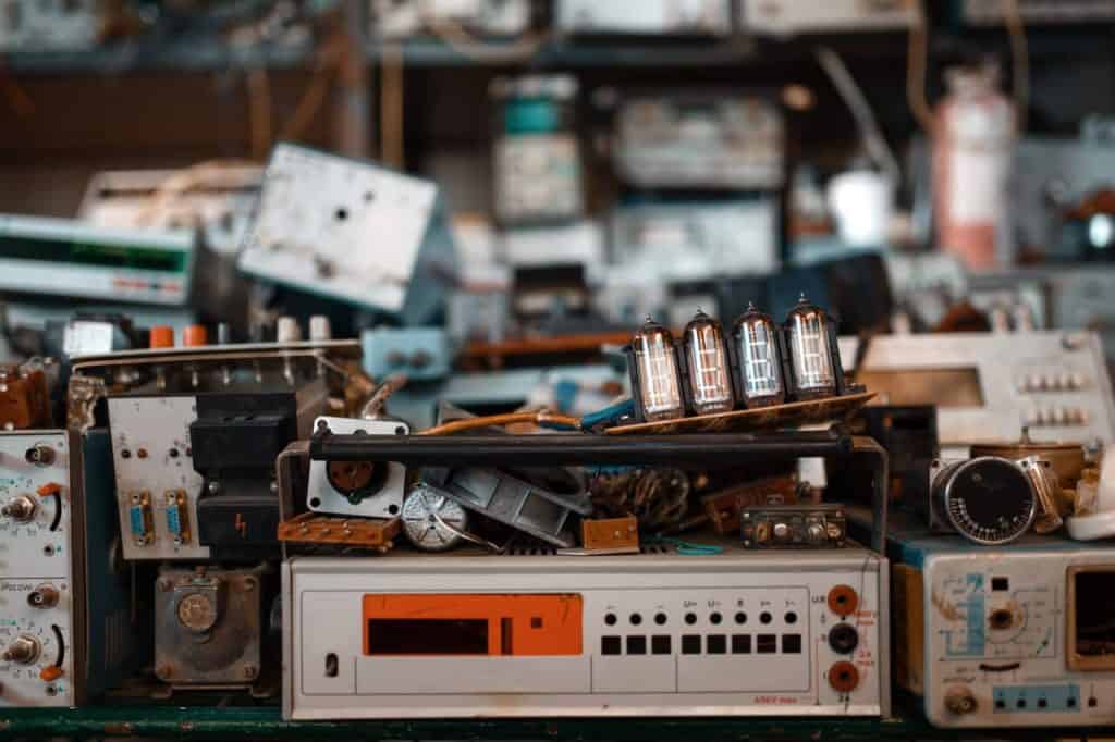 A cluttered workspace filled with vintage electronic equipment, including old circuit boards, dials, and vacuum tubes. This collection of retro technology evokes nostalgia while highlighting the importance of electronic recycling in Atlanta GA to preserve the past responsibly.