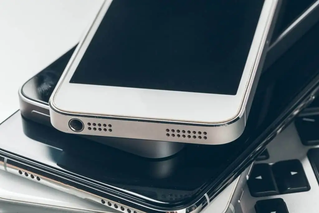 A close-up of a stack of smartphones placed on a laptop keyboard highlights technology and connectivity, echoing the importance of electronic recycling in Atlanta, GA. The phones, with visible speaker holes and ports, underscore the city's commitment to responsible e-waste management.
