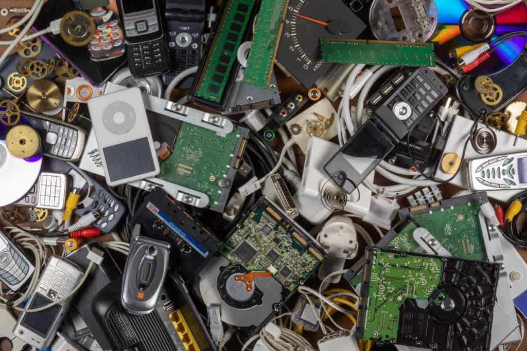 A chaotic assortment of electronic waste, including circuit boards, old mobile phones, MP3 players, wires, and RAM sticks, piled in a heap at the Electronic Waste Drop Off Box in Atlanta GA.