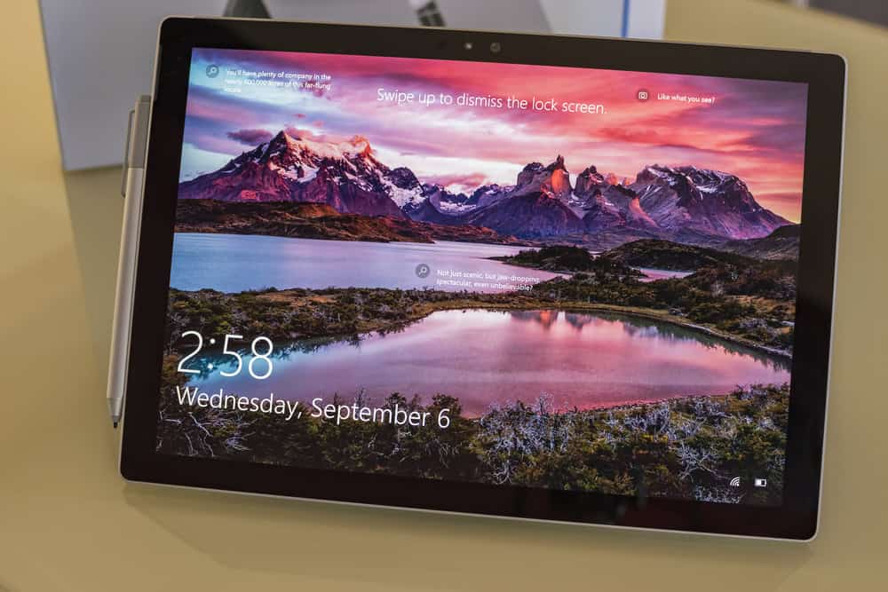A tablet displaying a lock screen with a scenic mountain view and a lake. Text includes the time "2:58" and date "Wednesday, September 6." As the colorful sunset graces the sky, remember to recycle laptops and other devices like this one for responsible electronics waste disposal.