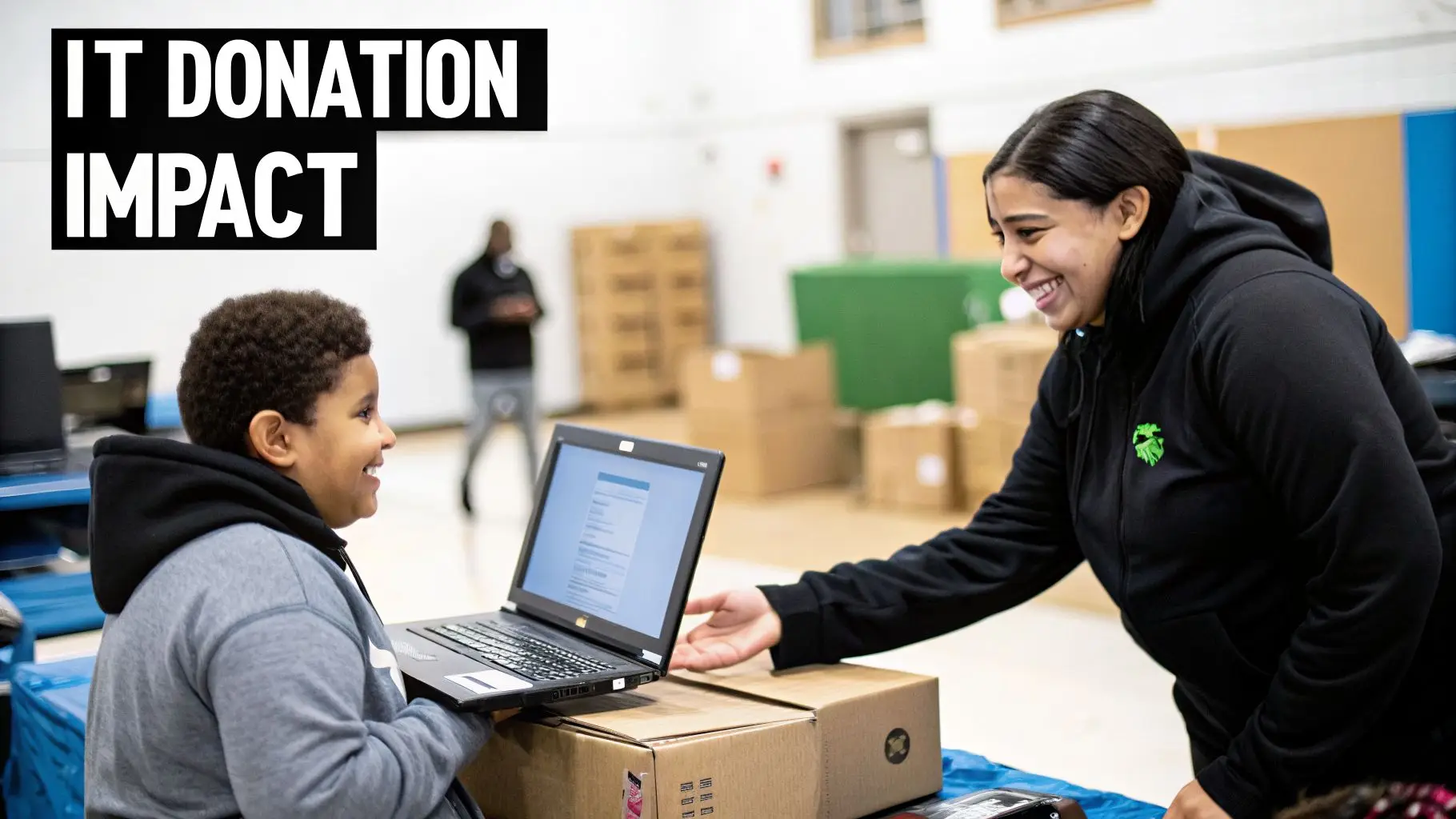 A smiling boy uses a laptop while a woman assists him at an IT donation event.