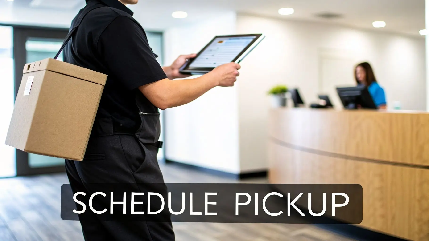 A service worker in a black uniform holds a tablet and carries a brown package for pickup.