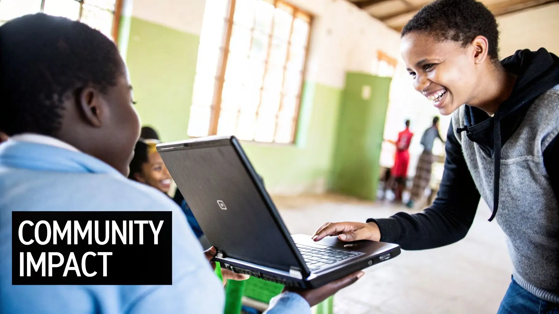 Two students smiling and collaborating on a laptop in a bright community learning environment.