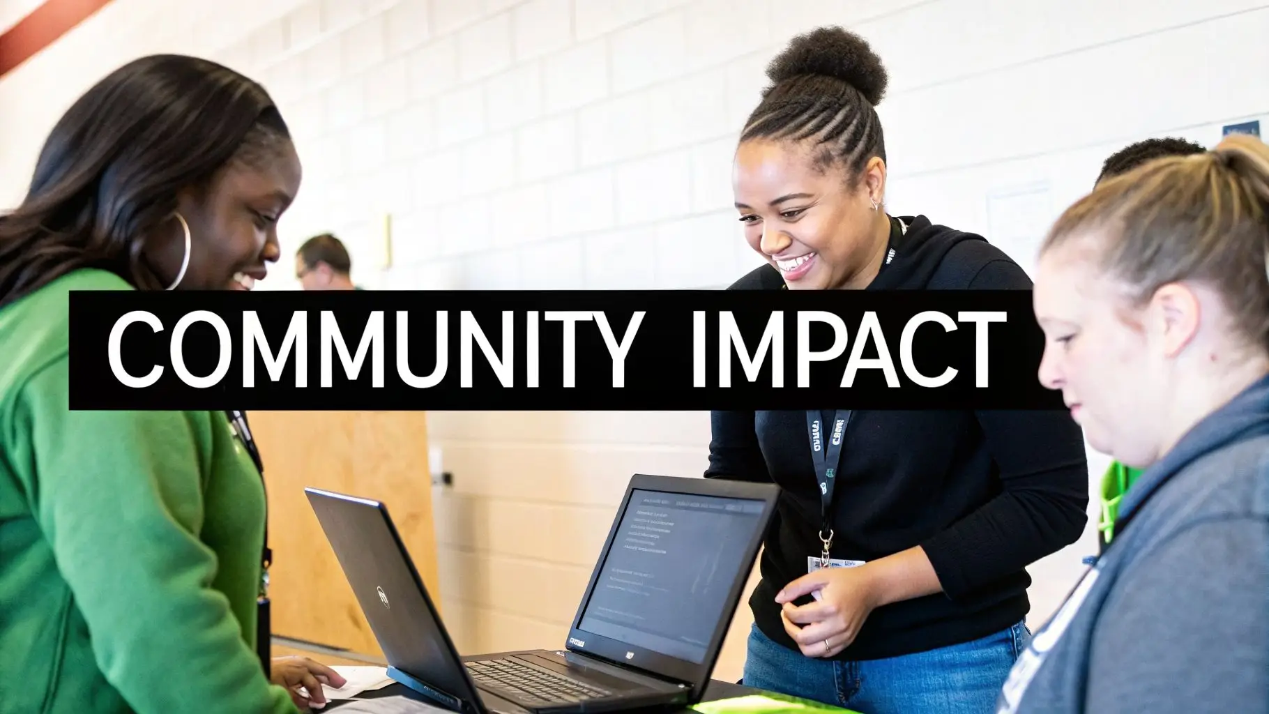 Three young women smiling and engaging with laptops at a vibrant community impact event.