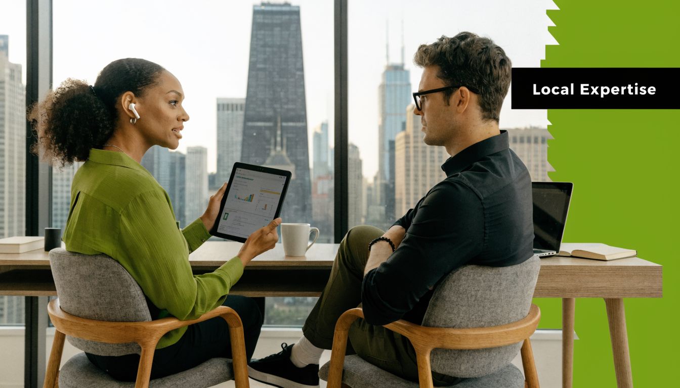 A woman and man discussing business data on a tablet in a high-rise office overlooking Chicago.