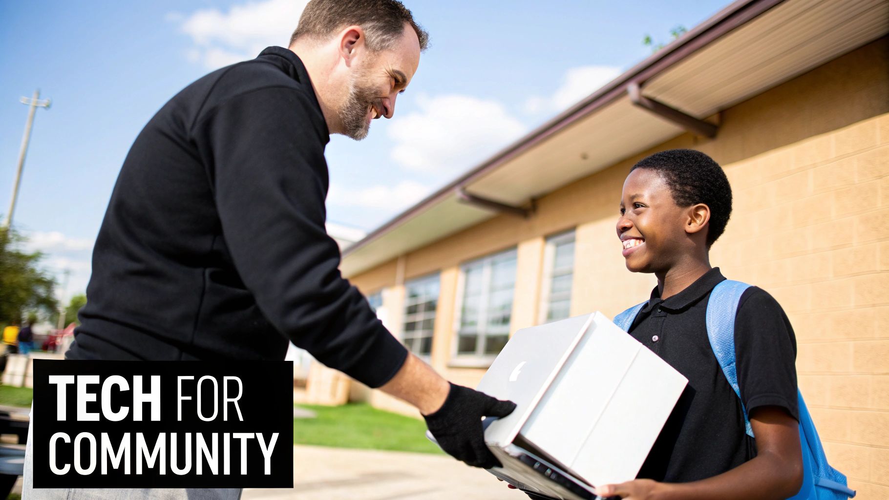A man smiles as he hands electronics in a box to a happy boy, promoting tech for community.