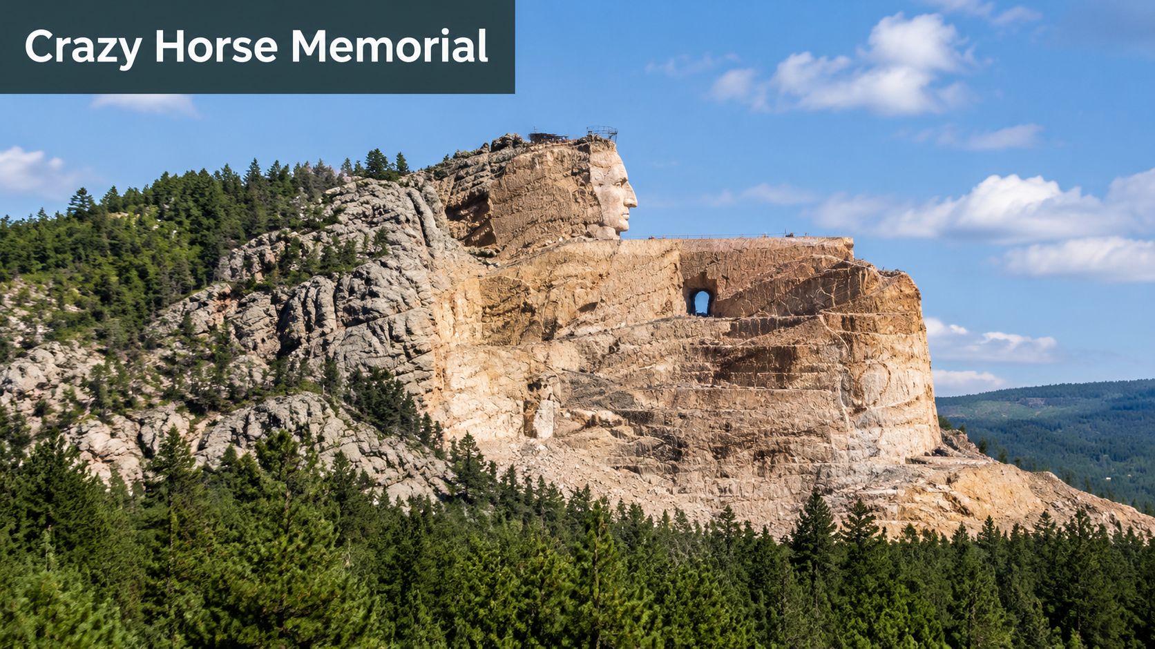 A wide angle view of the massive Crazy Horse Memorial sculpture carved into a mountain in South Dakota.